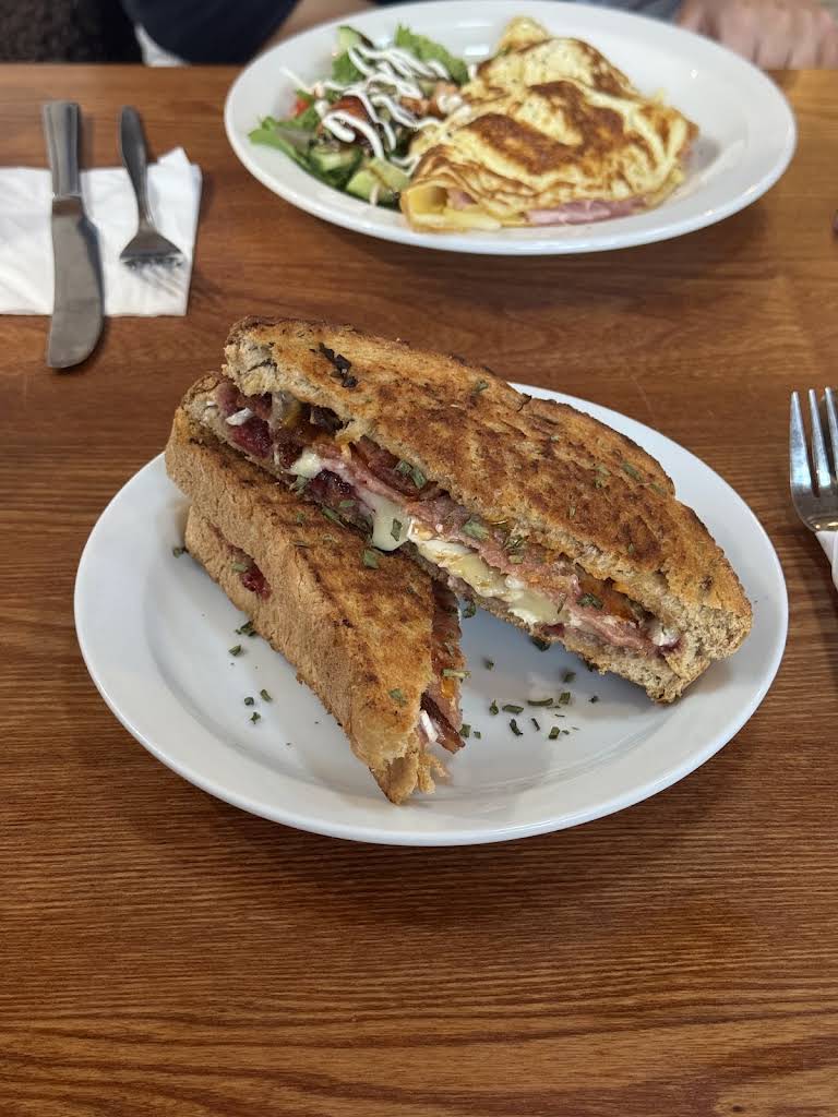 A toasted sandwich on a white plate at Cafe 25, with another café dish on the table behind it.